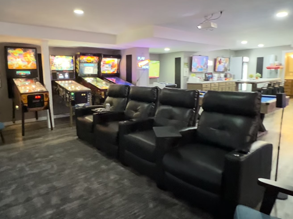 A back view of the theater area showing the seating and pinballs, as well as the flooring and carpet.